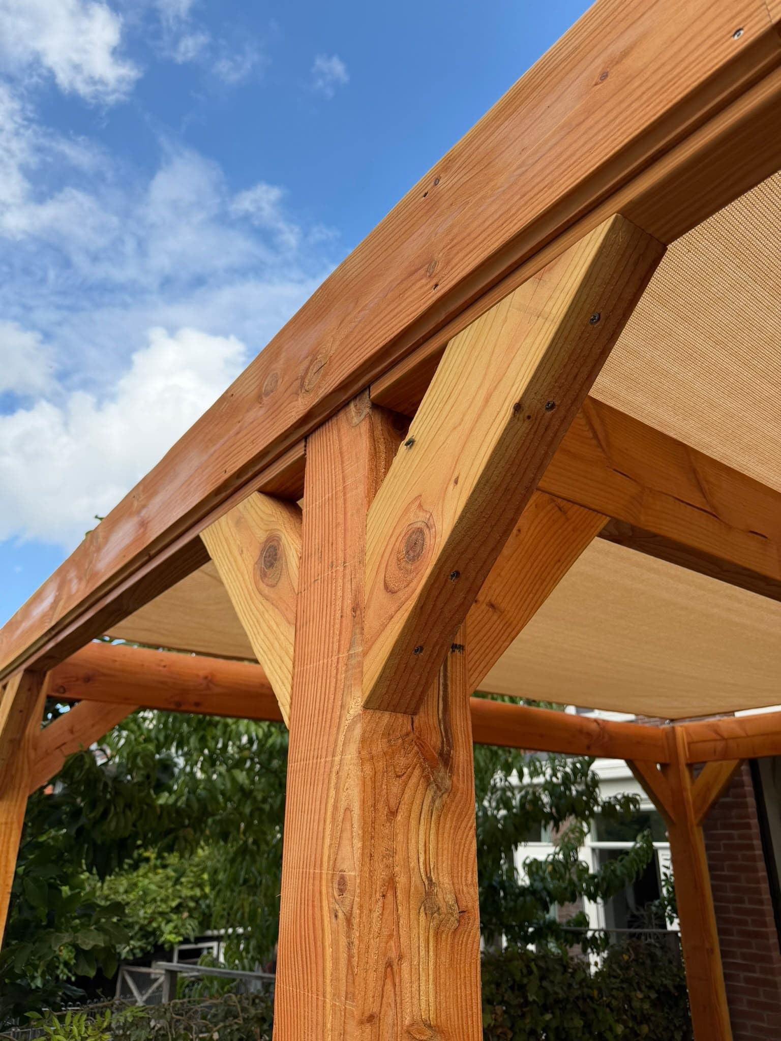 Detail van de overkapping: een staander met twee schuine schoren onder de ligger, vastgezet met schroeven.