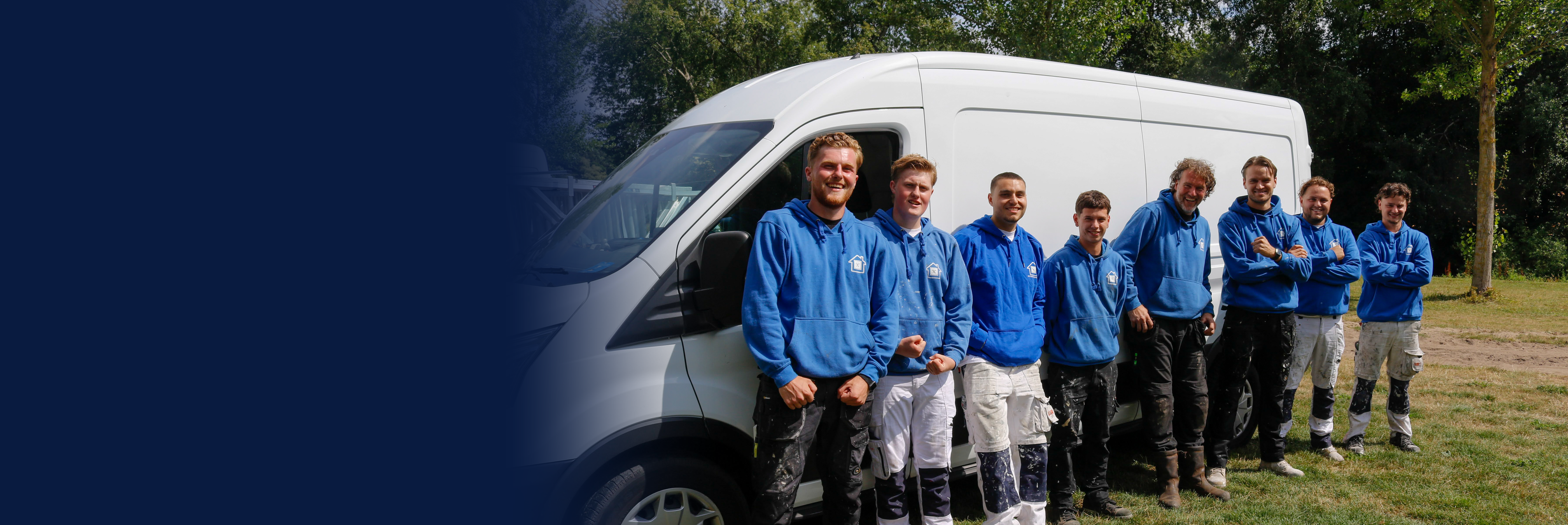 Het team van NB Projectbouw: acht vakmensen in blauwe hoodies naast de bus