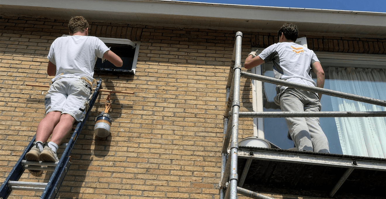 Twee schilders op een ladder en steiger aan de gevel van een woning