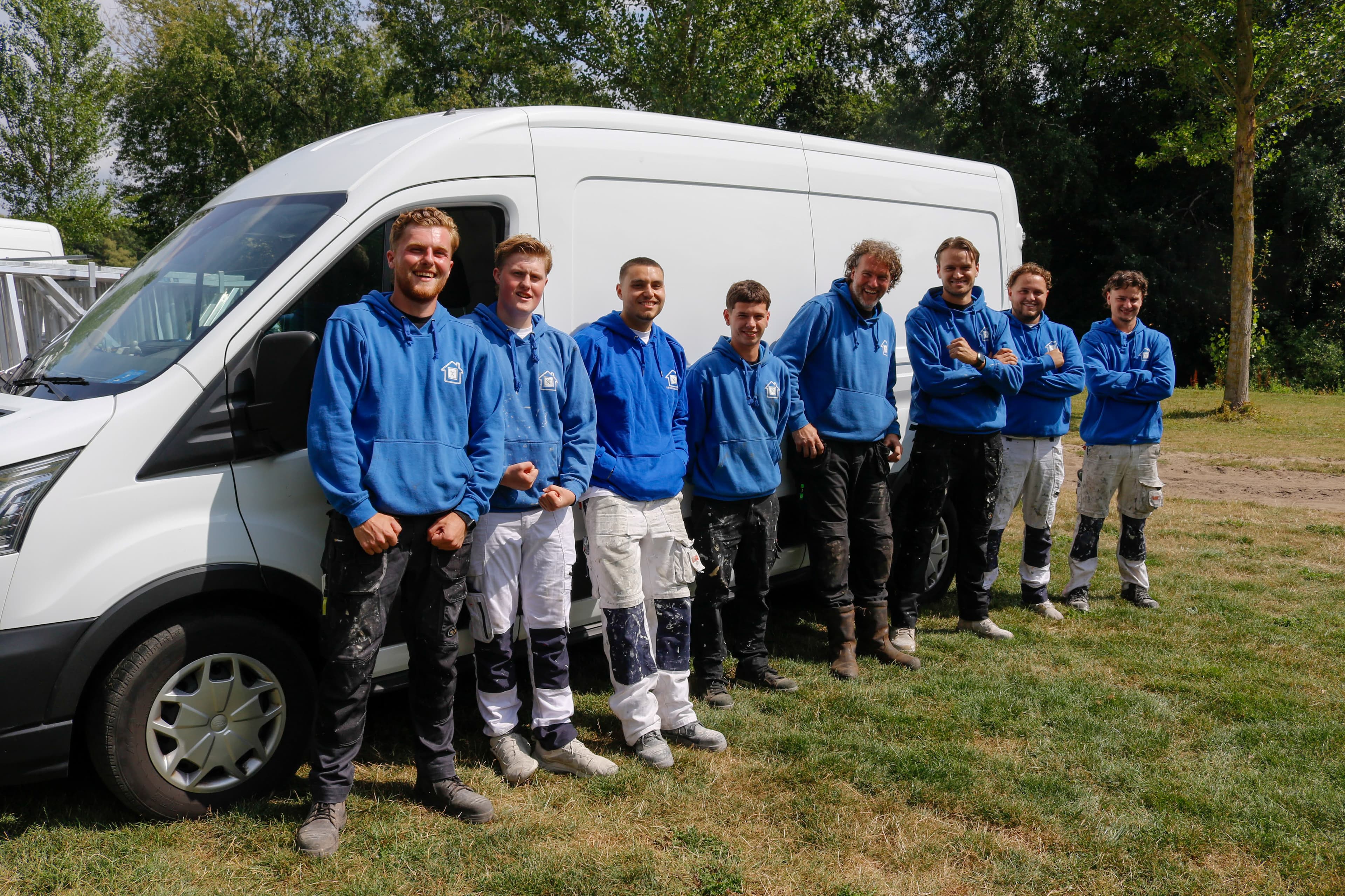 Het team van NB Projectbouw in werkkleding naast een bedrijfsbus.